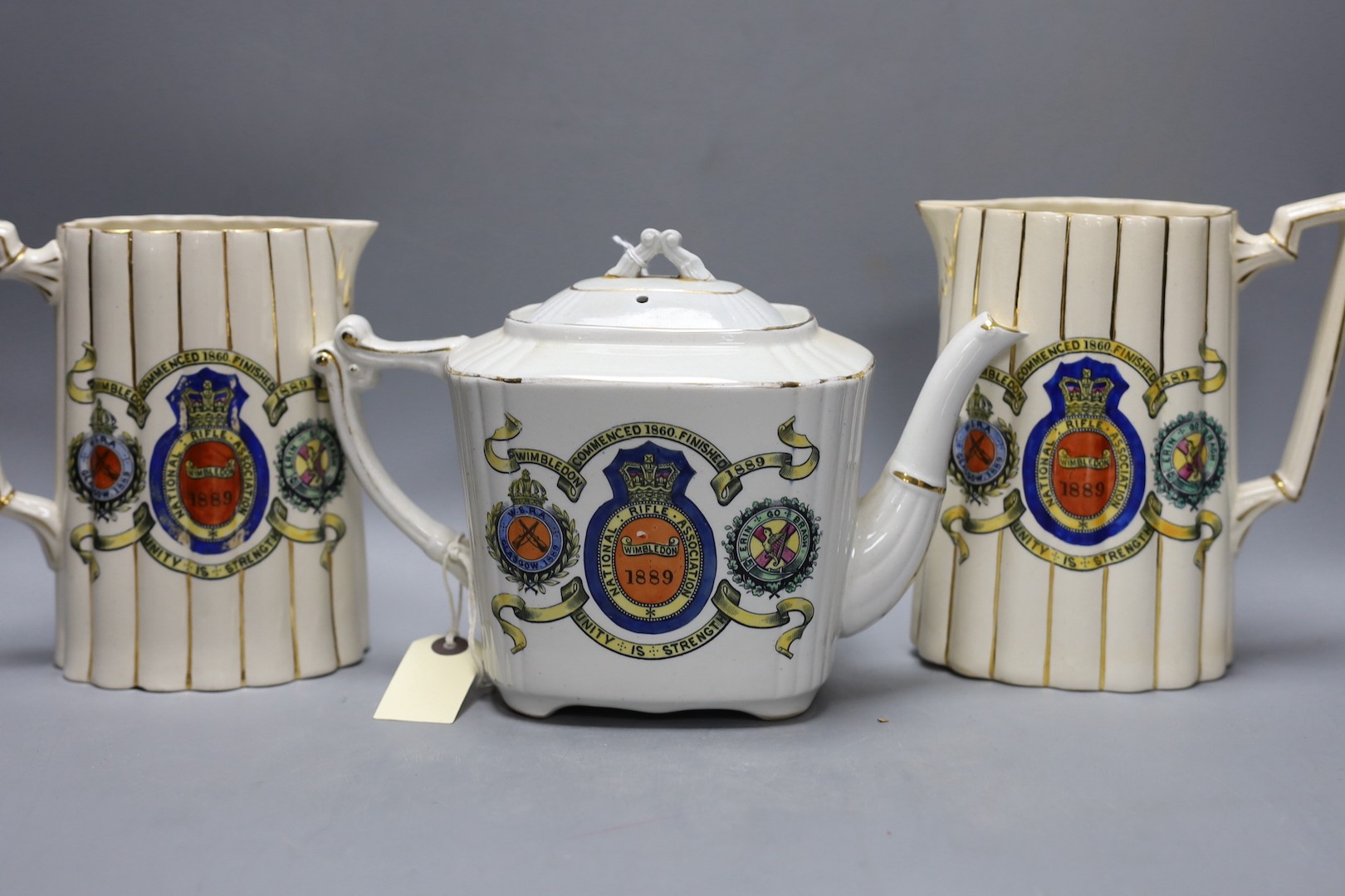 National Rifle Association Wimbledon 1889 - A group of Staffordshire commemorative pottery, including two water jugs, 18 cm high, and three matching beakers, a teapot and cover, a tray, together with a WW1 mug